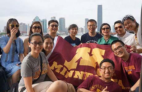 International alumni with a UMN banner in front of the Shanghai skyline