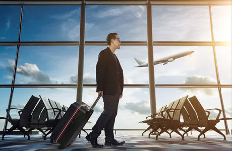 Man walking through airport pulling a suitcase