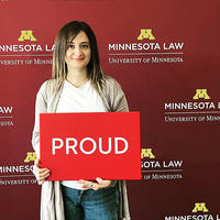 Shaghek Manjikian holding a "proud" sign in front of a Minnesota Law background