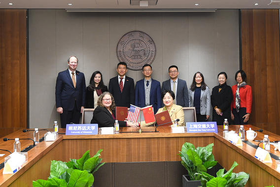 University leaders pose in a board room with a U.S. and China flag