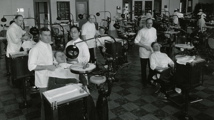 Dentistry students in white uniforms with patients