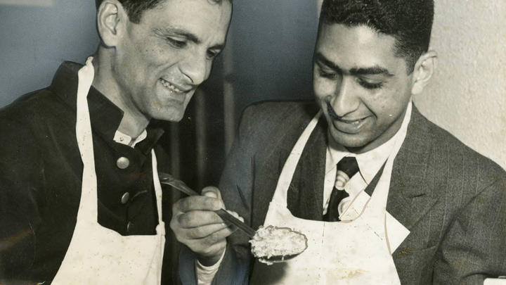 Student holding a spoonful of rice as another student looks on