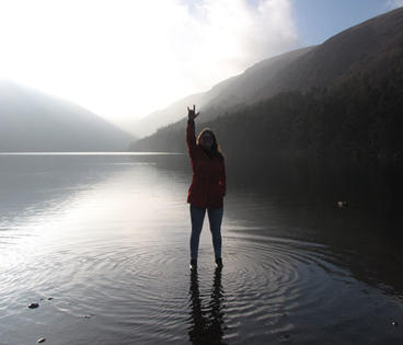 person standing in front of water and mountains