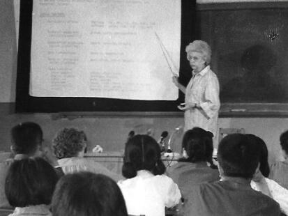 Teacher pointing to a projector screen in front of students