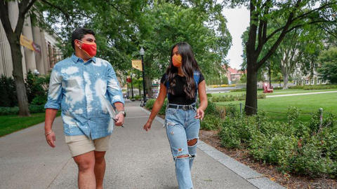 Two students wearing face masks walk on Northrop Mall