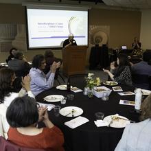 Attendees clap as Director Karen Brown speaks behind a lectern